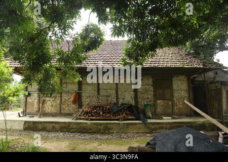 Ein altes Haus mit Holzsäulen und Holzbalken, Erdwänden und gekacheltem Dach in Dien Bien, Vietnam. Das Haus ist sehr warm im Winter und kühl im Sommer. Stockfoto