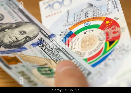 Banknotendesign der BRICS-Gruppe und 100 US-Dollar . Finanz- und Wirtschaftskonzept. Gemeinsame Währung der BRICS-Länder. Nahaufnahme Stockfoto