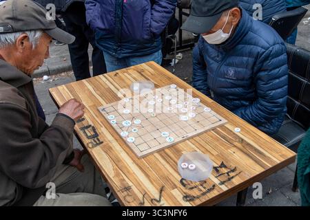 Seoul, Südkorea-30. März 2025; Mann sitzt an einem kleinen Tisch auf der Straße und spielt traditionelles Spiel von Janggi oder Koreanischem Schach mit etwas Zuschauern Stockfoto