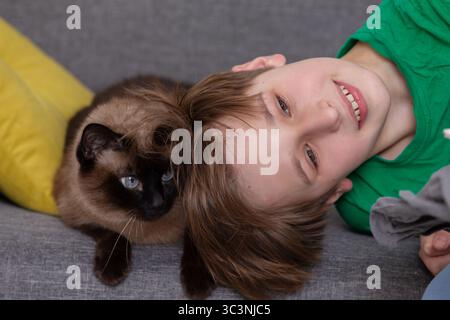Kinder liegen auf dem Sofa und eine Katze in der Nähe. Stockfoto