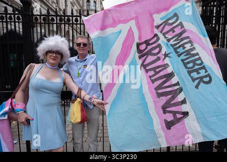 London, Großbritannien. 26. Juli 2025. Ein Paar, das vor der Downing Street steht, hält eine Flagge mit der Aufschrift „Remember Brianna“ in Bezug auf Brianna Ghey, das 16-jährige britische Transgender-Mädchen, das ermordet wurde, als Tausende von Transgender-Menschen und Unterstützern auf dem Parlamentsplatz zur jährlichen Trans Pride-Kundgebung marschieren. Die 2019 von Lucia Blayke gegründete Veranstaltung wächst weiter und ist sowohl eine Feier als auch eine Antwort auf die Diskriminierung von Transgender-Menschen, die Freiheit und Gleichheit fordern. Quelle: Ron Fassbender/Alamy Live News Stockfoto