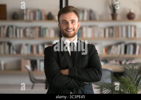 Selbstbewusster junger Geschäftsmann in formeller Kleidung, der im Büro posiert Stockfoto
