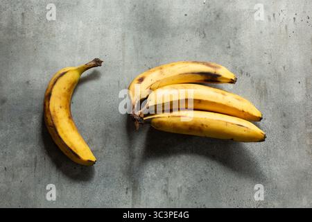 Eine Ansicht von oben nach unten auf eine einzelne Banane, die von einem Bananenbund getrennt ist. Stockfoto