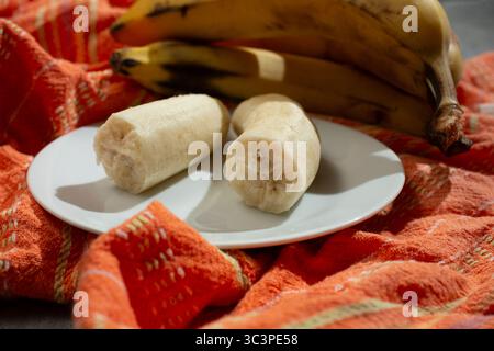 Ein Blick auf eine zerbrochene Banane auf einem Teller, in einem Stillleben. Stockfoto