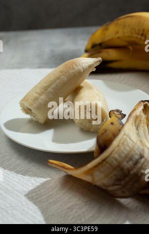 Ein Blick auf eine zerbrochene Banane auf einem Teller, in einem Stillleben. Stockfoto