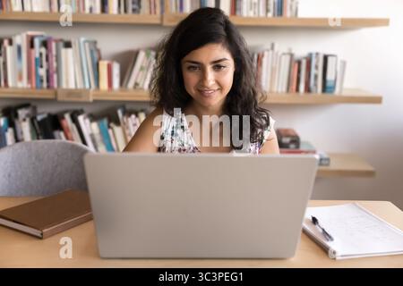 Frau, die mit einem Laptop am Arbeitsplatz in Arbeit oder Studium eingetaucht ist Stockfoto