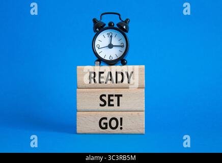 Symbol bereit Set Go. Concept Words Ready Set auf Holzblöcken. Wunderschöner blauer Hintergrund mit Wecker. Business- und Ready-Go-Konzept. Kopieren Stockfoto