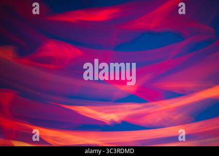 Abstraktes Material mit Bewegungselementen im Hintergrund, das durch Wind auf Dunkelblau fließt. Dynamisch und lebendig, evoziert Energie, Feuer oder einen Tanz aus Neonlichtern Stockfoto