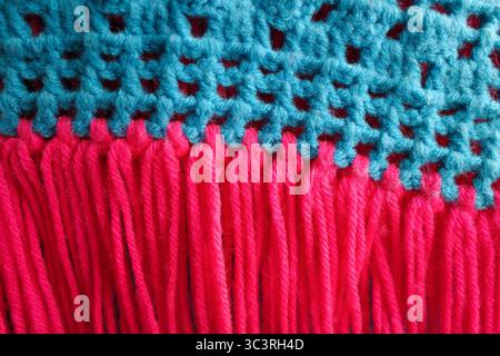 Nahaufnahme strukturiert aus einem leuchtend blauen und rosa Häkel- oder Strickstoff. Stockfoto
