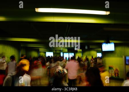 Eine Menschenmenge läuft durch ein hell beleuchtetes grünes Inneres, dynamisches Verschieben der Verschlusszeit Stockfoto