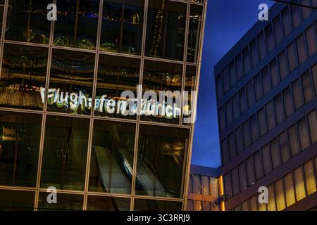 Beleuchtetes Schild zum Flughafen Zürich reflektiert nachts auf einem modernen Bürogebäude im Flughafen Kloten, Zürich, Kanton Zürich, Schweiz Stockfoto
