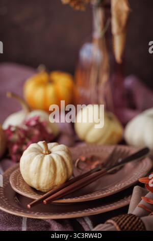 Gemütliches Herbstessen mit rustikalen Kürbissen und weichen rosa Tellern Stockfoto