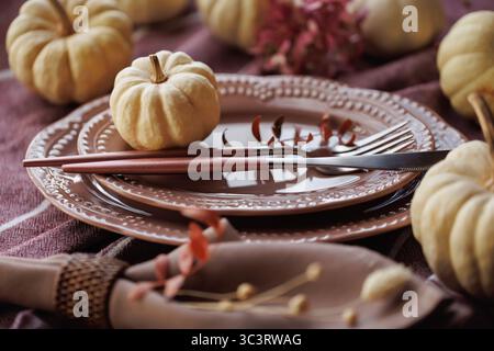 Festlicher Herbsttisch mit weißen Kürbissen und Tellern im Vintage-Stil Stockfoto