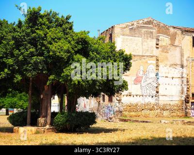 Padre Pio Statue unter Baum im Bezirk Kalsa mit religiösem Wandgemälde an der alten Mauer, Palermo, Sizilien Stockfoto