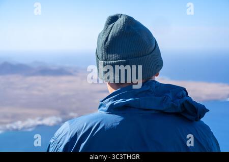 Ein Mann mit Hut schaut auf eine wunderschöne Landschaft mit Meer. Stockfoto