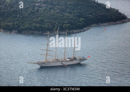 Dubrovnik, Kroatien. Juli 2025. Das viermastige Segelschiff STAR FLYER (Star Clippers Cruises) liegt in der Nähe der Insel Lokrum, Adria, von oben gesehen. Weit entfernt von den riesigen Kreuzfahrtschiffen, die in Port Gruž anlegen, verkörpert dieses elegante, weißgeschwungene Großschiff den Aufstieg der langsamen Fahrt und eine nachhaltigere Alternative angesichts der wachsenden Sorgen über Übertourismus in Dubrovnik, einer Stadt, die zum UNESCO-Weltkulturerbe gehört und vom Massentourismus überwältigt wird. Das Boot im Stil eines Clippers verleiht der kroatischen Küste und der Insel, die von dichter mediterraner Flora und Wäldern bedeckt ist, eine malerische Präsenz. Quelle: Kevin Izorce/Alamy Live News Stockfoto
