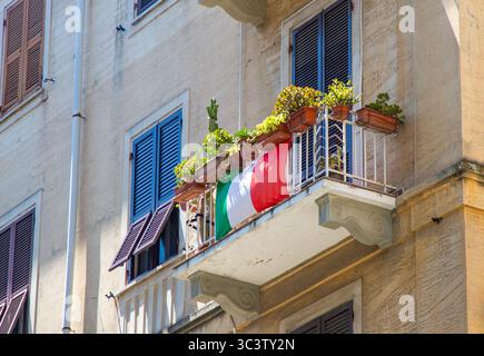 Holzläden an den Fenstern. Italienische Flagge und Blumen auf dem offenen italienischen Balkonhaus. La Spezia Italien. Stockfoto