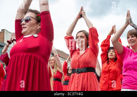 Birmingham, Großbritannien. Juli 2025. 300 Menschen treffen sich zusammen, um eine Tanzroutine namens Most Wuthering Heights Ever in Kings Heath, Birmingham, Großbritannien, aufzuführen. Die Teilnehmer, alle in rot gekleidet, wurden von Jess Phillips, Labour-Abgeordneter für Yardley, Birmingham, angesprochen, bevor sie das Musikvideo für Kate Bushs ikonisches Lied „Wuthering Heights“ reproduzierten. Frau Phillips schließt sich dem expressiven Tanz an. Die Veranstaltung sammelt Gelder für Women's Empowerment and Recovery Educators und ANAWIM Charitations. Quelle: Peter Lopeman/Alamy Live News Stockfoto