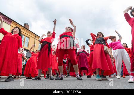 Birmingham, Großbritannien. Juli 2025. 300 Menschen treffen sich zusammen, um eine Tanzroutine namens Most Wuthering Heights Ever in Kings Heath, Birmingham, Großbritannien, aufzuführen. Die Teilnehmer, alle in rot gekleidet, wurden von Jess Phillips, Labour-Abgeordneter für Yardley, Birmingham, angesprochen, bevor sie das Musikvideo für Kate Bushs ikonisches Lied „Wuthering Heights“ reproduzierten. Die Veranstaltung sammelt Gelder für Women's Empowerment and Recovery Educators und ANAWIM Charitations. Quelle: Peter Lopeman/Alamy Live News Stockfoto