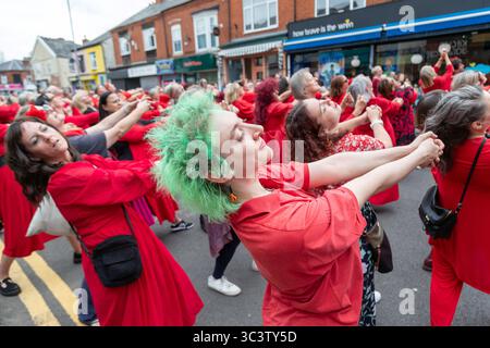 Birmingham, Großbritannien. Juli 2025. 300 Menschen treffen sich zusammen, um eine Tanzroutine namens Most Wuthering Heights Ever in Kings Heath, Birmingham, Großbritannien, aufzuführen. Die Teilnehmer, alle in rot gekleidet, wurden von Jess Phillips, Labour-Abgeordneter für Yardley, Birmingham, angesprochen, bevor sie das Musikvideo für Kate Bushs ikonisches Lied „Wuthering Heights“ reproduzierten. Die Veranstaltung sammelt Gelder für Women's Empowerment and Recovery Educators und ANAWIM Charitations. Quelle: Peter Lopeman/Alamy Live News Stockfoto