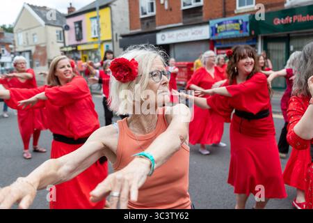 Birmingham, Großbritannien. Juli 2025. 300 Menschen treffen sich zusammen, um eine Tanzroutine namens Most Wuthering Heights Ever in Kings Heath, Birmingham, Großbritannien, aufzuführen. Die Teilnehmer, alle in rot gekleidet, wurden von Jess Phillips, Labour-Abgeordneter für Yardley, Birmingham, angesprochen, bevor sie das Musikvideo für Kate Bushs ikonisches Lied „Wuthering Heights“ reproduzierten. Die Veranstaltung sammelt Gelder für Women's Empowerment and Recovery Educators und ANAWIM Charitations. Quelle: Peter Lopeman/Alamy Live News Stockfoto