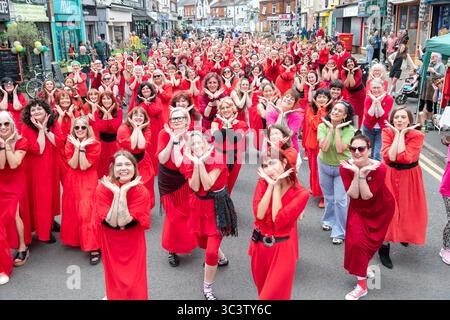 Birmingham, Großbritannien. Juli 2025. 300 Menschen treffen sich zusammen, um eine Tanzroutine namens Most Wuthering Heights Ever in Kings Heath, Birmingham, Großbritannien, aufzuführen. Die Teilnehmer, alle in rot gekleidet, wurden von Jess Phillips, Labour-Abgeordneter für Yardley, Birmingham, angesprochen, bevor sie das Musikvideo für Kate Bushs ikonisches Lied „Wuthering Heights“ reproduzierten. Die Veranstaltung sammelt Gelder für Women's Empowerment and Recovery Educators und ANAWIM Charitations. Quelle: Peter Lopeman/Alamy Live News Stockfoto