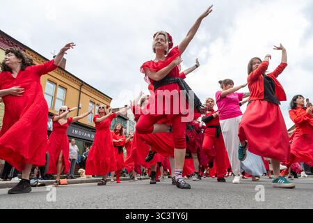 Birmingham, Großbritannien. Juli 2025. 300 Menschen treffen sich zusammen, um eine Tanzroutine namens Most Wuthering Heights Ever in Kings Heath, Birmingham, Großbritannien, aufzuführen. Die Teilnehmer, alle in rot gekleidet, wurden von Jess Phillips, Labour-Abgeordneter für Yardley, Birmingham, angesprochen, bevor sie das Musikvideo für Kate Bushs ikonisches Lied „Wuthering Heights“ reproduzierten. Die Veranstaltung sammelt Gelder für Women's Empowerment and Recovery Educators und ANAWIM Charitations. Quelle: Peter Lopeman/Alamy Live News Stockfoto