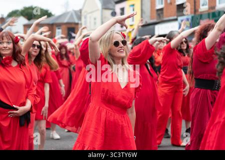 Birmingham, Großbritannien. Juli 2025. 300 Menschen treffen sich zusammen, um eine Tanzroutine namens Most Wuthering Heights Ever in Kings Heath, Birmingham, Großbritannien, aufzuführen. Die Teilnehmer, alle in rot gekleidet, wurden von Jess Phillips, Labour-Abgeordneter für Yardley, Birmingham, angesprochen, bevor sie das Musikvideo für Kate Bushs ikonisches Lied „Wuthering Heights“ reproduzierten. Die Veranstaltung sammelt Gelder für Women's Empowerment and Recovery Educators und ANAWIM Charitations. Quelle: Peter Lopeman/Alamy Live News Stockfoto