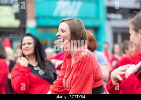 Birmingham, Großbritannien. Juli 2025. 300 Menschen treffen sich zusammen, um eine Tanzroutine namens Most Wuthering Heights Ever in Kings Heath, Birmingham, Großbritannien, aufzuführen. Die Teilnehmer, alle in rot gekleidet, wurden von Jess Phillips, Labour-Abgeordneter für Yardley, Birmingham, angesprochen, bevor sie das Musikvideo für Kate Bushs ikonisches Lied „Wuthering Heights“ reproduzierten. Frau Phillips schließt sich dem expressiven Tanz an. Die Veranstaltung sammelt Gelder für Women's Empowerment and Recovery Educators und ANAWIM Charitations. Quelle: Peter Lopeman/Alamy Live News Stockfoto