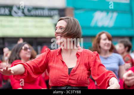 Birmingham, Großbritannien. Juli 2025. 300 Menschen treffen sich zusammen, um eine Tanzroutine namens Most Wuthering Heights Ever in Kings Heath, Birmingham, Großbritannien, aufzuführen. Die Teilnehmer, alle in rot gekleidet, wurden von Jess Phillips, Labour-Abgeordneter für Yardley, Birmingham, angesprochen, bevor sie das Musikvideo für Kate Bushs ikonisches Lied „Wuthering Heights“ reproduzierten. Frau Phillips schließt sich dem expressiven Tanz an. Die Veranstaltung sammelt Gelder für Women's Empowerment and Recovery Educators und ANAWIM Charitations. Quelle: Peter Lopeman/Alamy Live News Stockfoto
