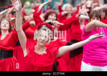 Birmingham, Großbritannien. Juli 2025. 300 Menschen treffen sich zusammen, um eine Tanzroutine namens Most Wuthering Heights Ever in Kings Heath, Birmingham, Großbritannien, aufzuführen. Die Teilnehmer, alle in rot gekleidet, wurden von Jess Phillips, Labour-Abgeordneter für Yardley, Birmingham, angesprochen, bevor sie das Musikvideo für Kate Bushs ikonisches Lied „Wuthering Heights“ reproduzierten. Die Veranstaltung sammelt Gelder für Women's Empowerment and Recovery Educators und ANAWIM Charitations. Quelle: Peter Lopeman/Alamy Live News Stockfoto