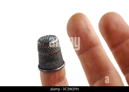 Finger der Hand mit Vintage Messingblütenblatt auf weißem Hintergrund. Stockfoto