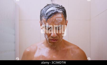 Trauriger Mann, der sich beim Duschen im Bad reflektiert Stockfoto