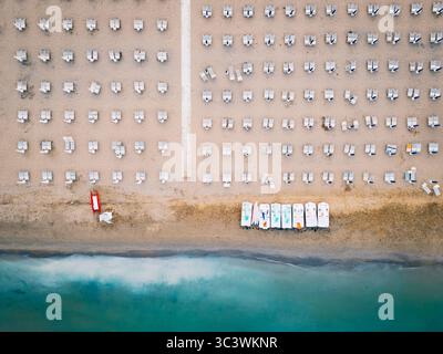 Luftaufnahme der symmetrischen Strandstühle und Tretboote an der Küste in Lignano, Italien Stockfoto