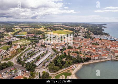 Panoramablick auf Porec, Kroatien, mit Blick auf die Küstenstadt, den Yachthafen, den Parkplatz, die roten Ziegeldächer und die umliegenden grünen Felder Stockfoto