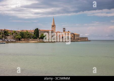 Blick auf die Halbinsel der historischen Altstadt von Porec von der Adria aus mit dem ikonischen Glockenturm der Euphrasian-Basilika, mittelalterlichen Steinbauten und der antiken Wa Stockfoto
