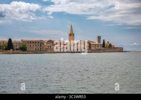 Blick auf die Halbinsel der historischen Altstadt von Porec von der Adria aus mit dem ikonischen Glockenturm der Euphrasian-Basilika, mittelalterlichen Steinbauten und der antiken Wa Stockfoto