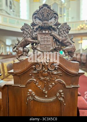Verzierte Holzstuhl-Rückenlehne mit geschnitzten Löwen und Wappen in der Michaeliskirche, Hamburg, Deutschland. Stockfoto