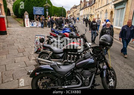 Eine Reihe geparkter Motorräder entlang der Church Street Calne beim jährlichen Fahrradtreffen 2025 mit historischen Gebäuden und Fußgängern. Stockfoto