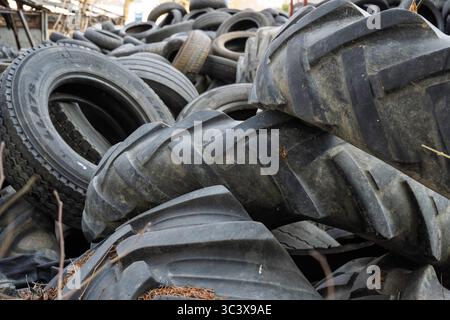 Großer Stapel gebrauchter Pkw- und Landwirtschaftsreifen auf einem Schrottplatz, bereit für das Recycling, was die Bedenken hinsichtlich der Umweltabfälle deutlich macht. Stockfoto