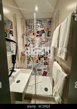 Modernes Hotelbad mit Glasdusche und dekorativer Wand im Stil einer Collage im NIU Hotel, Deutschland. Stockfoto