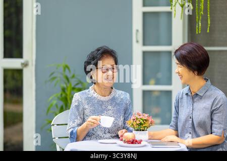 Glückliche asiatische Mutter mit ihrer erwachsenen Tochter unterhalten sich am Morgen entspannt. Stockfoto