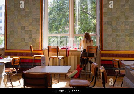 Jüngere Frau, die im Café der Kunstgalerie in Leeds am Laptop arbeitet Stockfoto