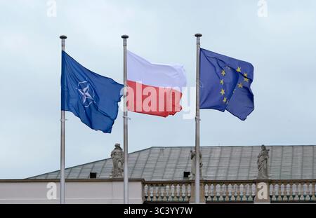 Die Flaggen der NATO, der EU und Polens winken nebeneinander im Wind Stockfoto