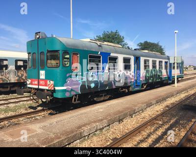 Farbenfrohe italienische Personenzüge und Eisenbahnwaggons in Bewegung durch Süditalien. Stockfoto