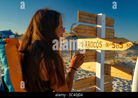 Junge weibliche, weiße europäische Kaukasierin, die Wegweiser nach Marokko beobachtet. Tavira-Portugal. Stockfoto