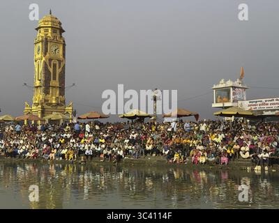 Uhrenturm und Versammlung von Menschen am Flussufer bei Tageslicht, Har Ki Pauri, Ganges, Haridwar, Uttarakhand, Indien Stockfoto