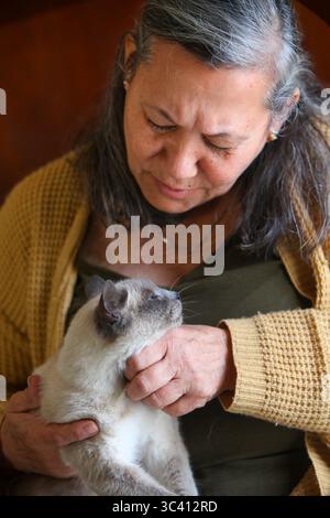 Nahaufnahme Porträt einer älteren latino-Frau, die ihre Katze im Haus liebevoll hält Stockfoto