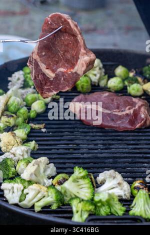 Rohe Rib-Eye-Steak über gegrilltem Gemüse heben Stockfoto