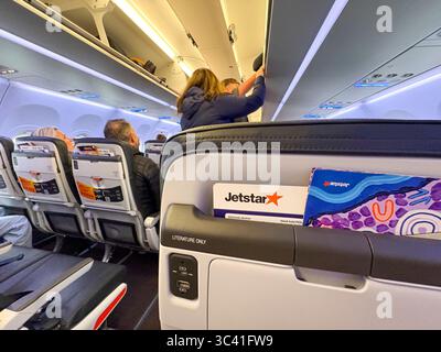 Jetstar Flugzeugkabine des Airbus A320 NEO Place Kabinengepäck im Gepäckraum über dem Dach auf dem Flug von Sydney Melbourne, Australien Stockfoto